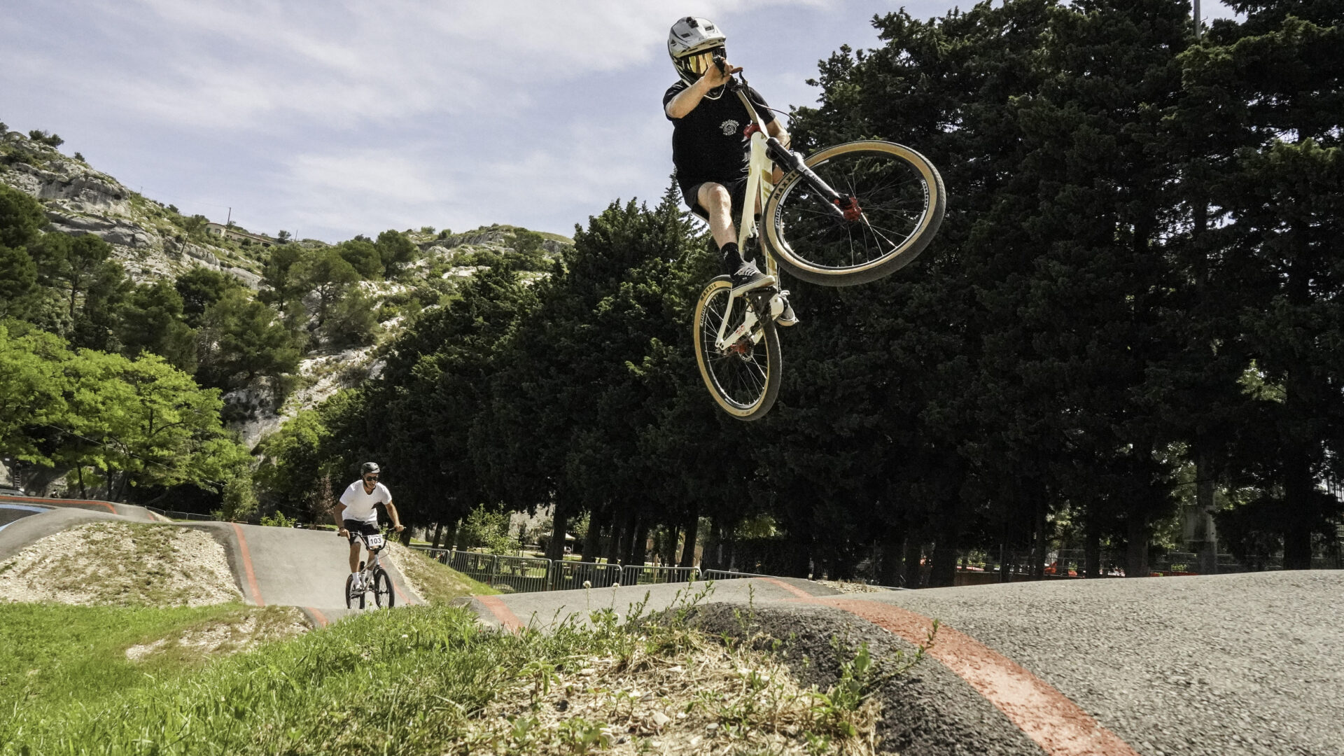 Jeune homme caqueé en BMX effectuant une accrobatrie dans les airs sur la piste de pump-track de la base de loisirs du Grenouillet, à Cavaillon
